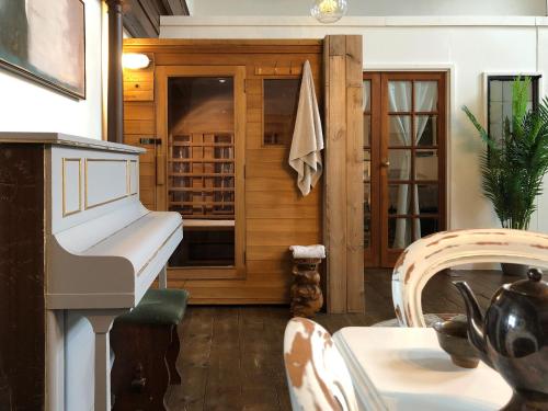 a dining room with a white piano and a dining table at Creative Norfolk Chapel with Piano and Sauna Sleeps 10 in Briston