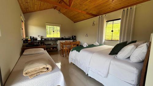 a bedroom with two beds and a kitchen with a table at Chalé Amanhecer in Aiuruoca