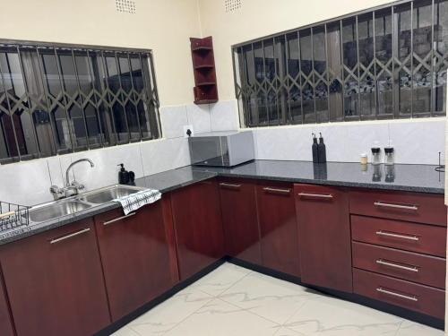 a kitchen with wooden cabinets and a sink at Ekhaya Loft in Mbabane