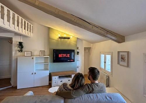 a man and woman sitting on a couch in a living room at Grand studio 31 m2 plus mezzanine centre ville grasse in Grasse