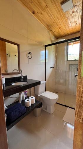 a bathroom with a toilet and a sink and a shower at Chalé Amanhecer in Aiuruoca