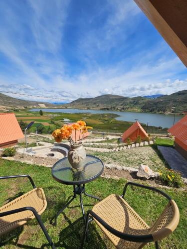 a table with chairs and a vase with flowers on it at Alpine Lake Lodge Hotel in Cajamarca