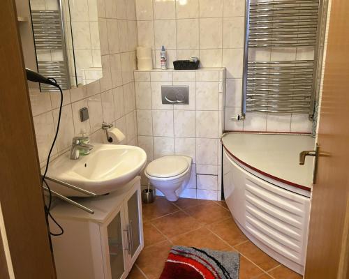 a bathroom with a sink and a tub and a toilet at Die Panorama-Wohnung-im-Grünem in Allensbach