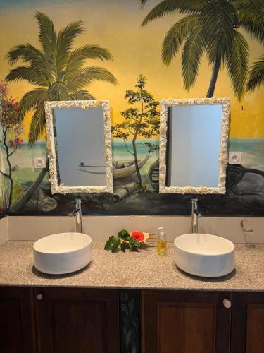 a bathroom with two sinks and a painting on the wall at Chez L'Avocatier in Sainte Marie