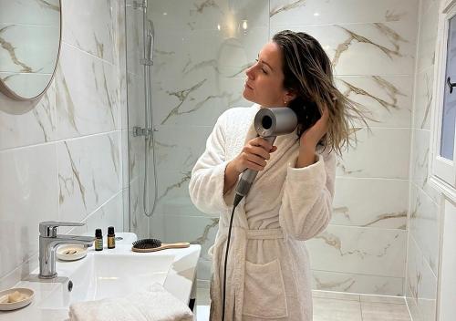 a woman standing in a bathroom blow drying her hair at Grand studio 31 m2 plus mezzanine centre ville grasse in Grasse