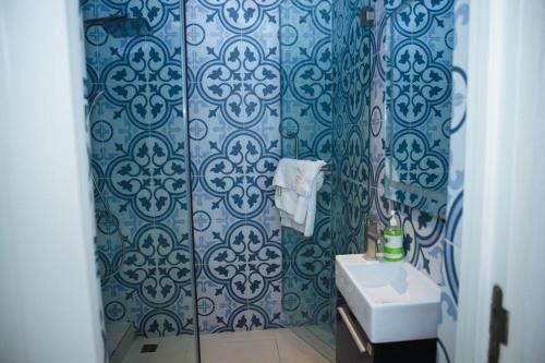 a bathroom with a sink and a shower with blue tiles at Billionaire Apartment in Lekki