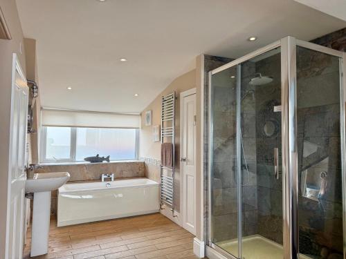 a bathroom with a tub and a shower and a sink at The View in Criccieth