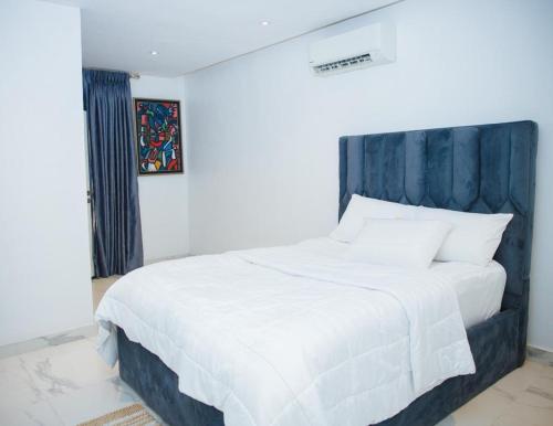 a bedroom with a white bed with a blue headboard at Billionaire Apartment in Lekki