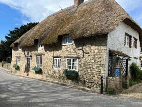 an old stone building with a thatched roof at Little Ivy in West Lulworth