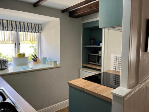 a kitchen with a stove top oven next to a window at Little Ivy in West Lulworth
