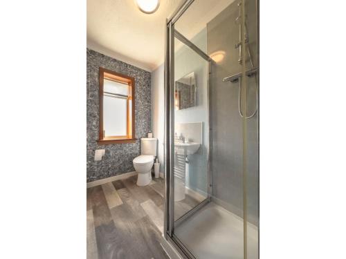 a bathroom with a glass shower and a toilet at The Otter Lodge in Broadford