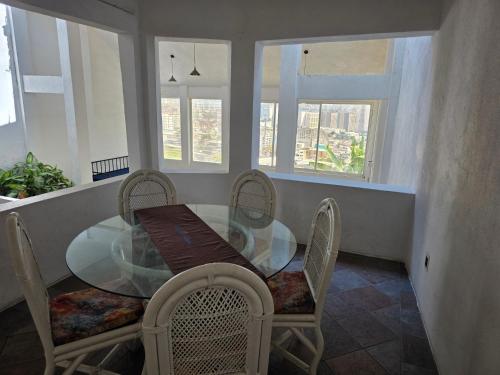 a dining room with a glass table and chairs at Casa Horizonte Azul Acapulco in Acapulco