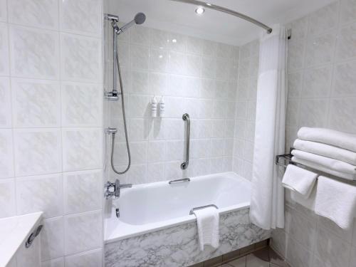 a bathroom with a tub and a shower with towels at The Aberdeen Dyce Hotel in Dyce