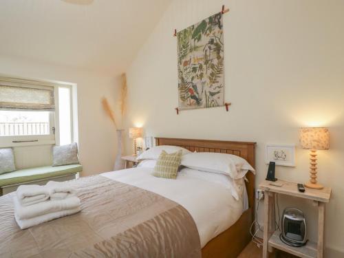 a bedroom with a bed with white sheets and a window at The Little Loft in Burford