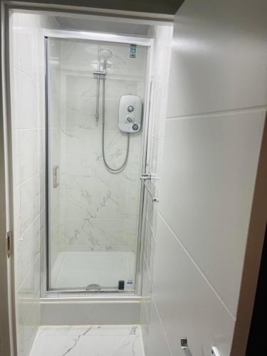 a shower with a glass door in a bathroom at 8 mins Drive from Heathrow - Double bedroom in shared accommodation - Cavalier Gardens in Hillingdon