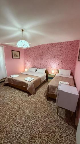 a bedroom with two beds and a pink wall at Casa Valeria in Pescia