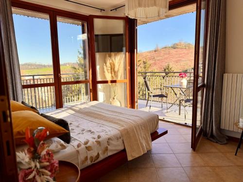 a bedroom with a bed and a balcony with a view at Elegant Penthouse LA BALCONATA - Wellness Retreat & Castle View in Tabiano