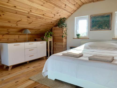 a bedroom with a white bed and a wooden ceiling at Domek Wśród Pól z Balia Jacuzzi in Rawa