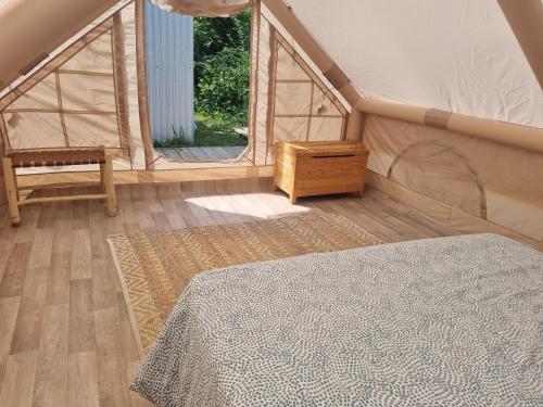 ein Schlafzimmer mit einem Bett, einem Stuhl und einem Fenster in der Unterkunft La tente de Tom in Salazie