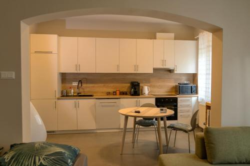 a kitchen with white cabinets and a small table at Emma Casa Apartmant FREE Private Parking with EV supply availability in Budapest