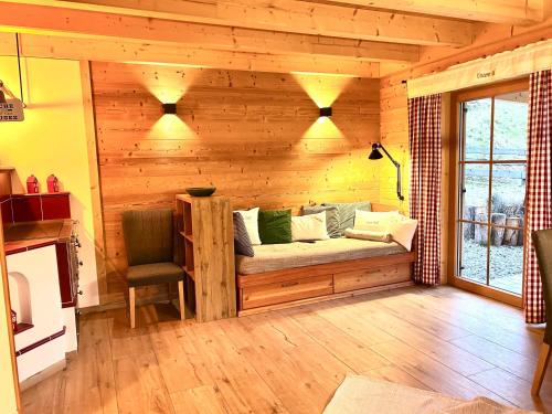 a living room with a couch on a wooden wall at Lärchenhaus ,,Unterer Brodl" in Kammersberg
