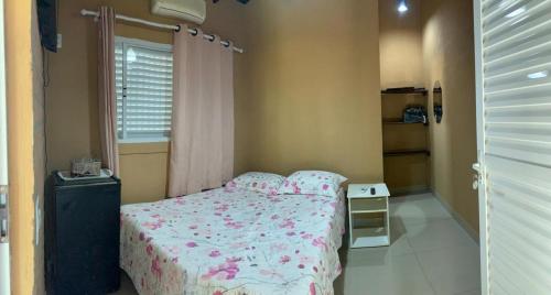 a small bedroom with a bed and a window at Casa Stúdio Uirá - suíte in Chapada dos Guimarães
