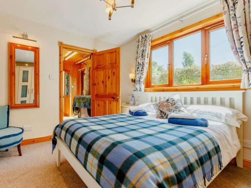 a bedroom with a bed and a chair and windows at 3 Bed in Crieff oc-88631 in Comrie