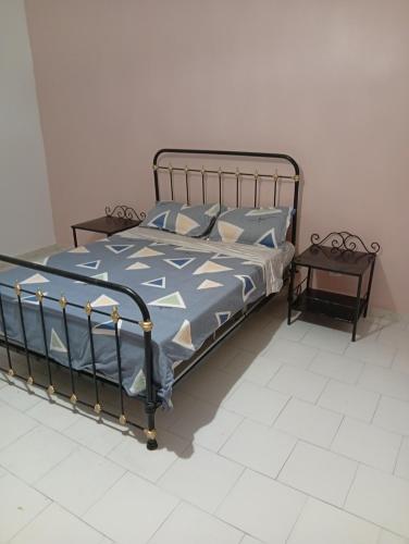 a bed with a blue comforter and a side table at Chez Mounas in Saint-Louis