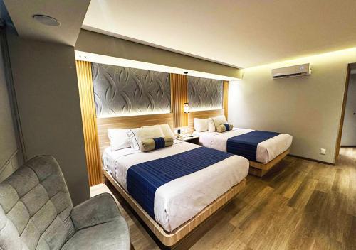 a hotel room with two beds and a chair at KALI Vallejo Mexico City in Mexico City