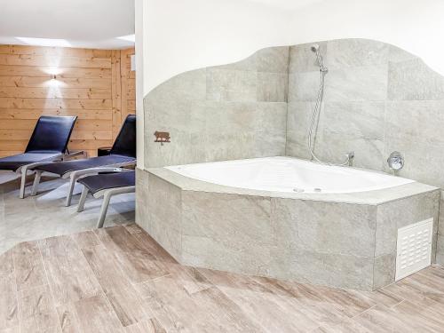 a bath tub in a room with two chairs at Apartment Lotus in Ovronnaz
