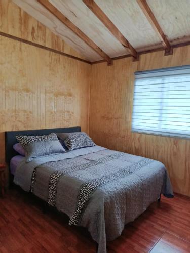 a bedroom with a bed in a room with a window at cabaña zoila N in Coñaripe