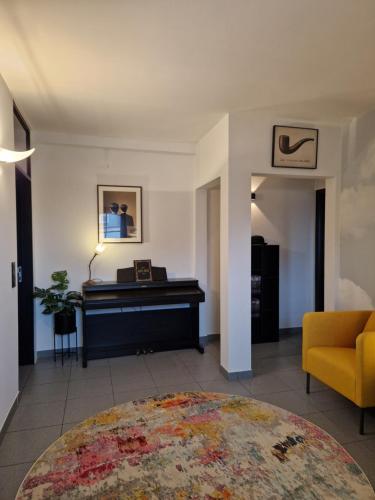 a living room with a piano and a yellow chair at Casa René in Aalter