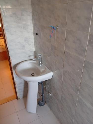 a bathroom with a white sink and a tiled wall at Chez Mounas in Saint-Louis