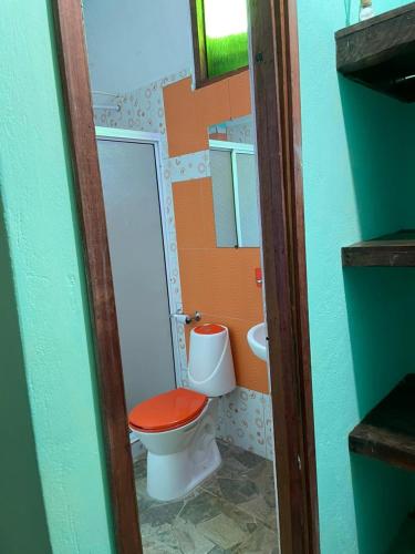 a small bathroom with a toilet with a red seat at Posada Kauai Experiencia de descanso y conexión en la selva in Mocoa