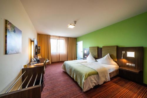 a hotel room with a bed and a green wall at Qualitel Wilnsdorf in Wilnsdorf