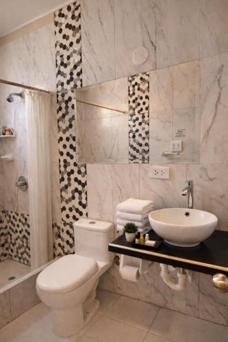 ein Badezimmer mit weißer Toilette und Waschbecken in der Unterkunft Ikasur Hotel in Ica