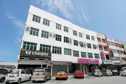 a white building with cars parked in a parking lot at Hotel Cheqinn in Ipoh