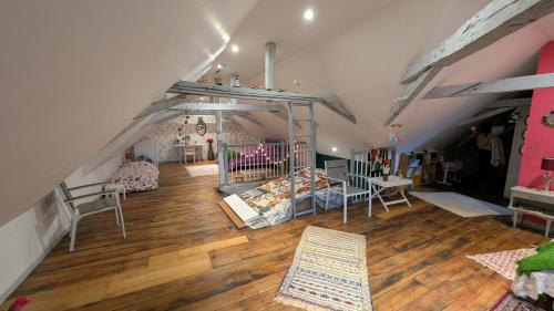 an attic room with a crib and tables and chairs at B&B chez Nicole in Montaut