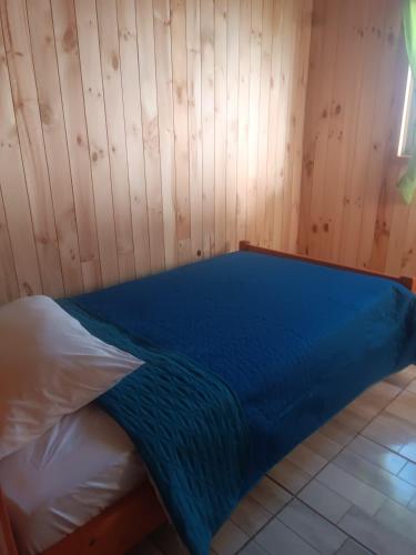 a bed in a room with a wooden wall at cabaña zoila ch in Coñaripe