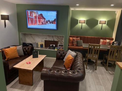 a living room with a couch and a tv on the wall at The Ostrich Inn, South Creake, Norfolk in South Creake
