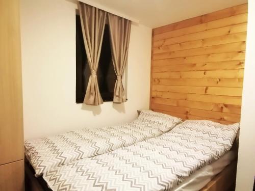 a bed with a wooden headboard and a window at PLANINSKI KUTAK Tara - Apartman 1 in Bajina Bašta