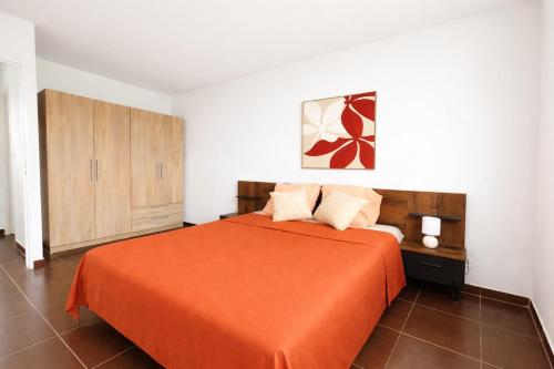 a bedroom with a bed with an orange bedspread at Villa Inelda in Saint-Paul