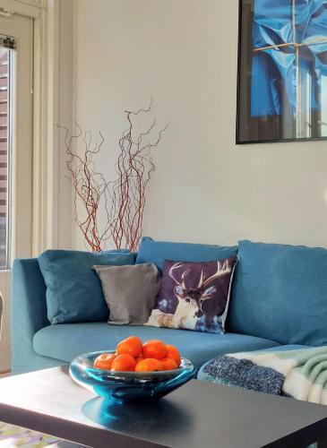 a blue couch with a bowl of oranges on a table at Levin Lumienkeli A6 in Levi