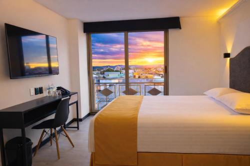 a hotel room with a bed and a desk and a window at Hotel Tamara in Puebla