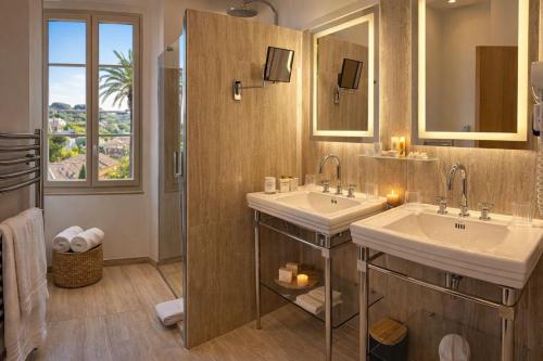 a bathroom with two sinks and two mirrors at La Bastide Du Port - Hôtel de Charme in Saint-Tropez