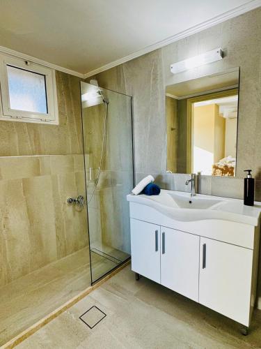 a bathroom with a white sink and a shower at Nautica Hotel Apartments in Stavromenos