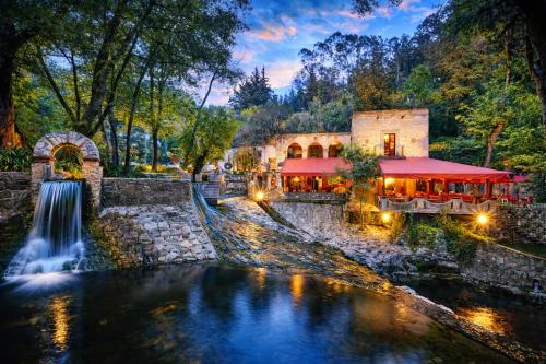 a restaurant next to a waterfall next to a river at Molino de los Reyes in Totolac