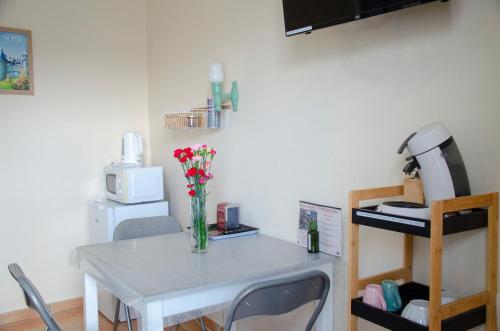 a white table with a vase of flowers on it at Le Relais du Jardin in Orbigny