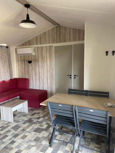 a living room with a table and a red couch at Camping Canet plage mobilhome 4 ou 6 personnes in Canet-en-Roussillon