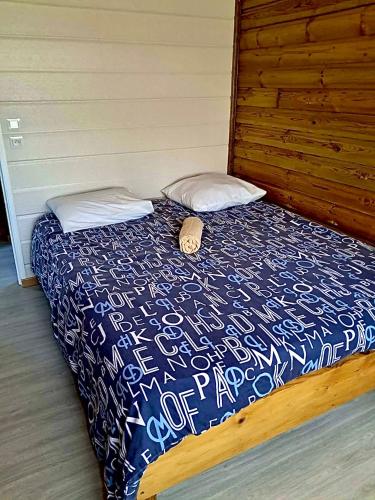 a bed with a blue and white comforter and two pillows at Ti Caz Bana in Le Tampon